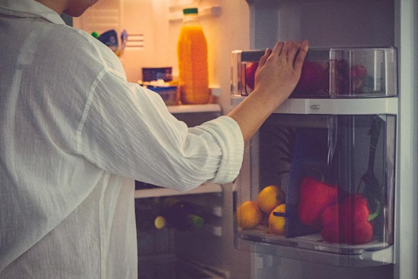Adult reaching into fridge at night
