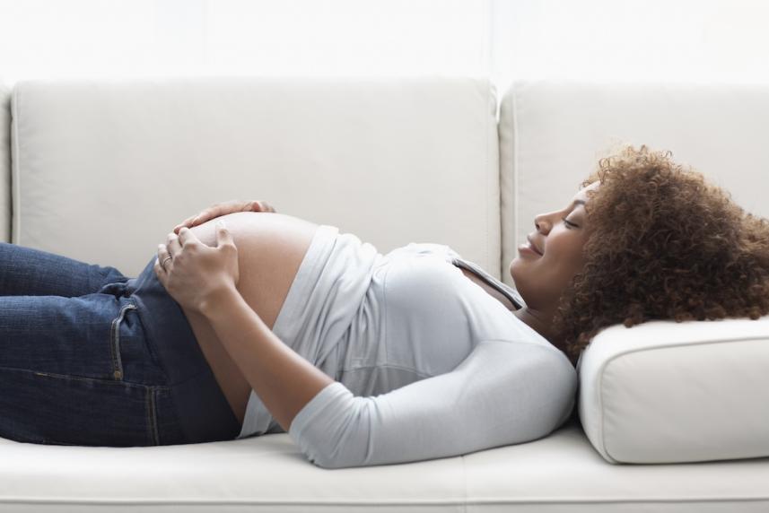 A pregnant woman lying down on a sofa